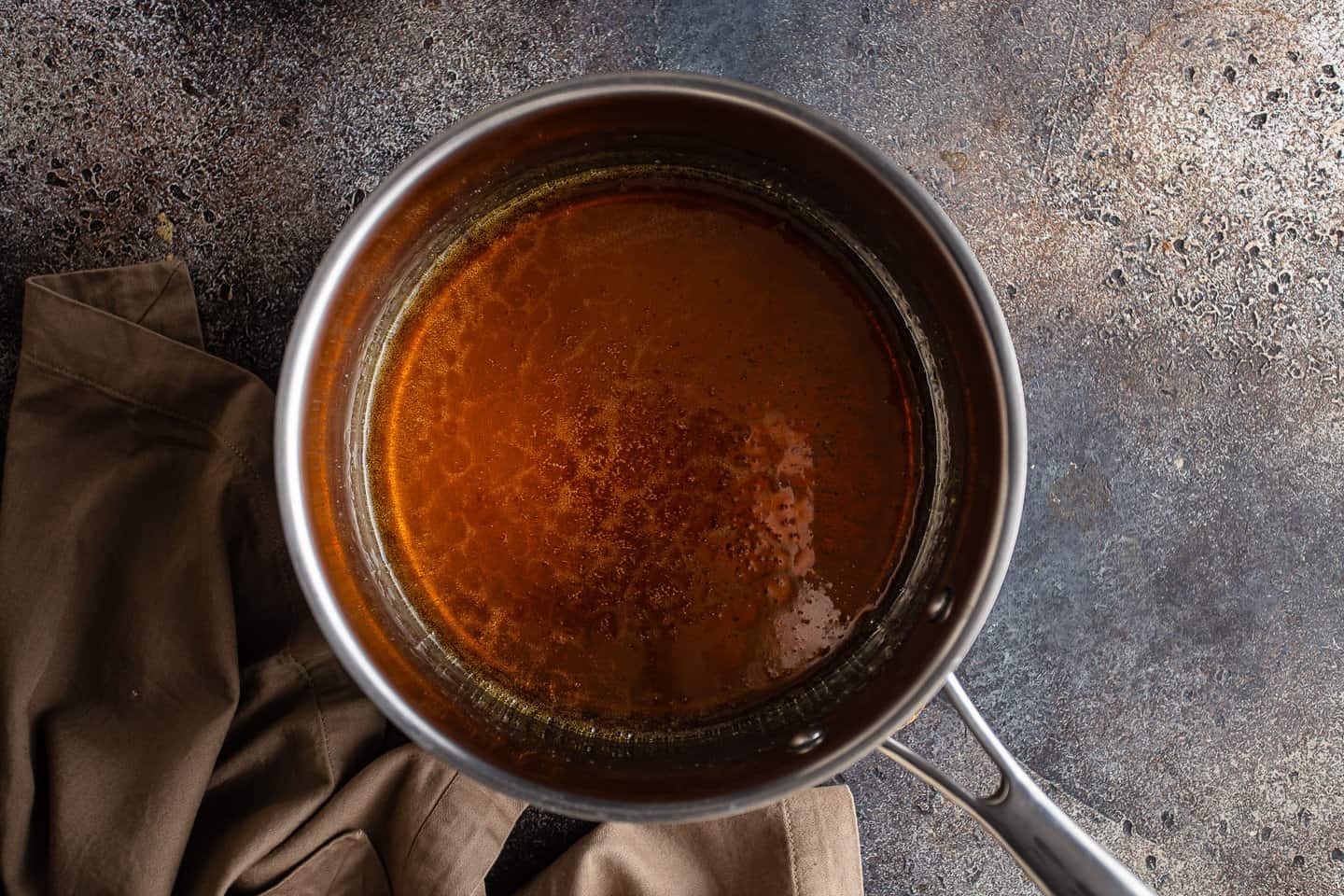 Caramelized sugar syrup in a medium stainless steel pot.