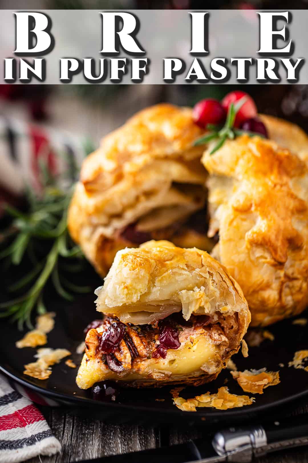 Baked brie with cranberries and pecans on a dark plate with fresh rosemary.
