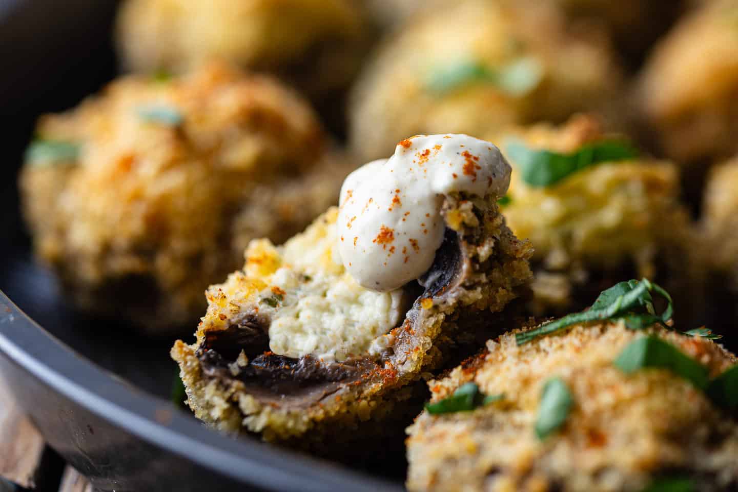 Cream cheese stuffed mushrooms, presented in a vintage cake pan with fresh herbs for garnish.