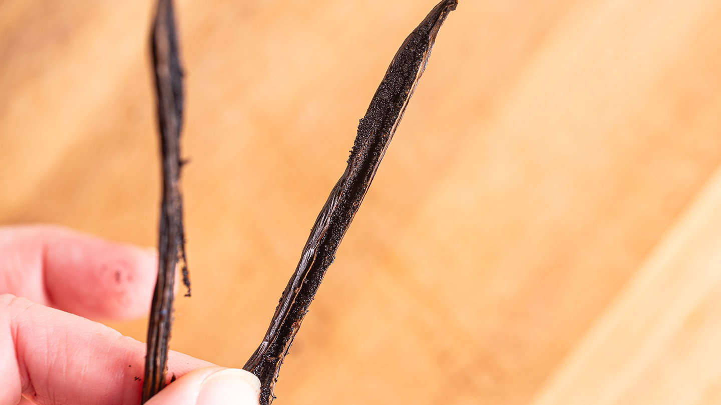 Close up of a split vanilla bean, showing the millions of tiny seeds inside.