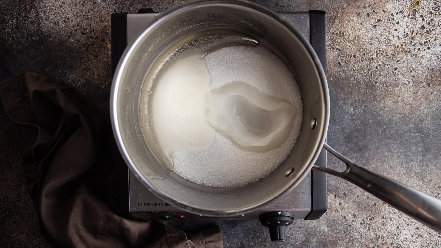 Cooking sugar, corn syrup, and water together in a medium pot.