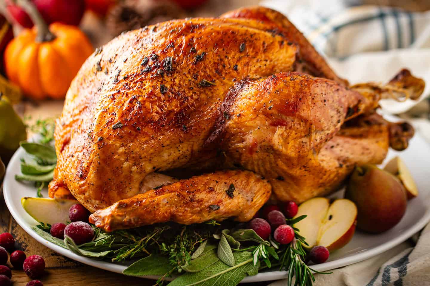 Roast turkey on a white platter with fresh herbs.