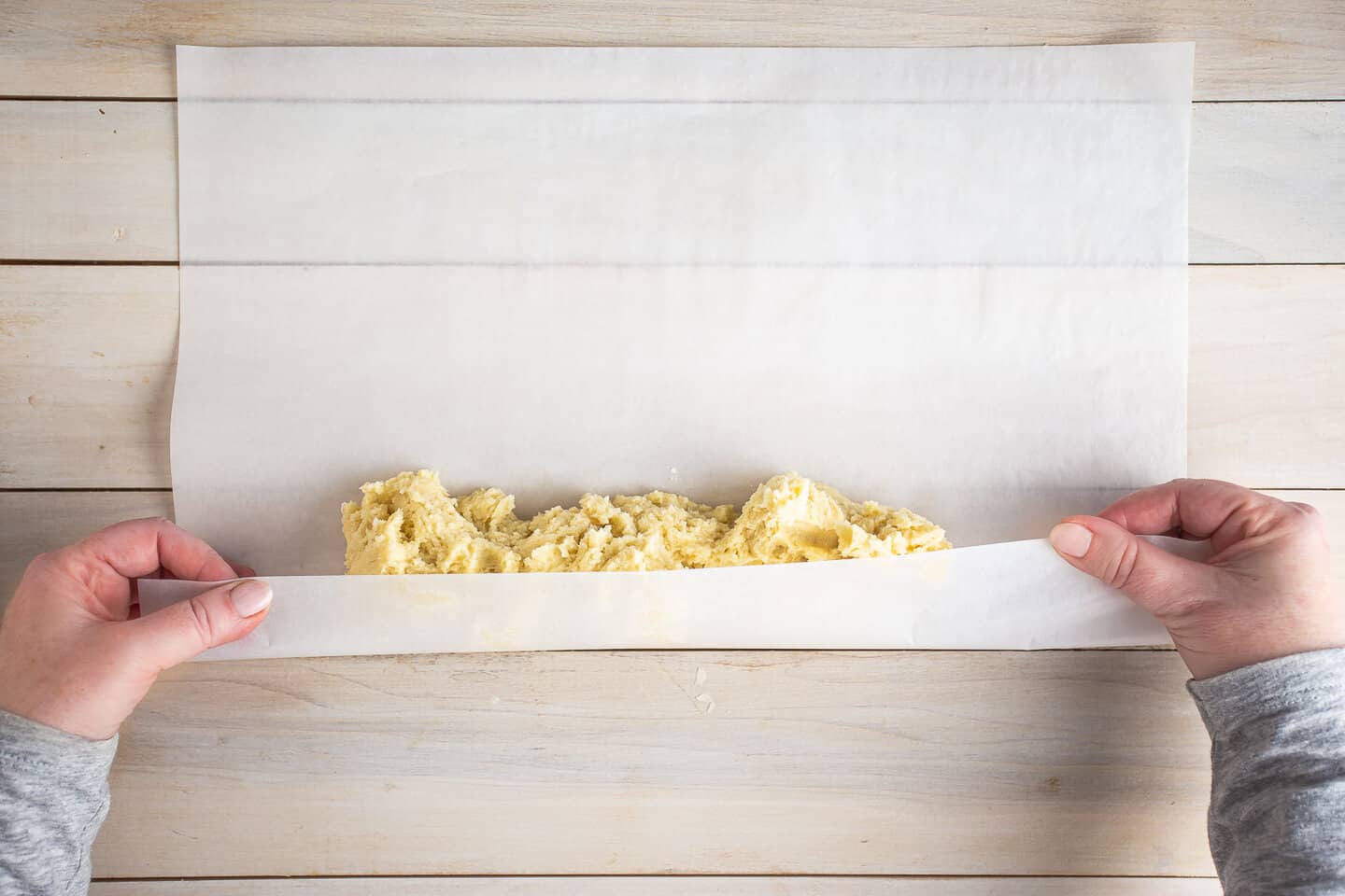 Rolling butter cookie dough into logs.