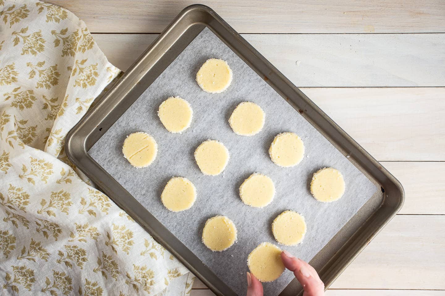 Unbaked butter cookies on a parchment-lined baking sheet.