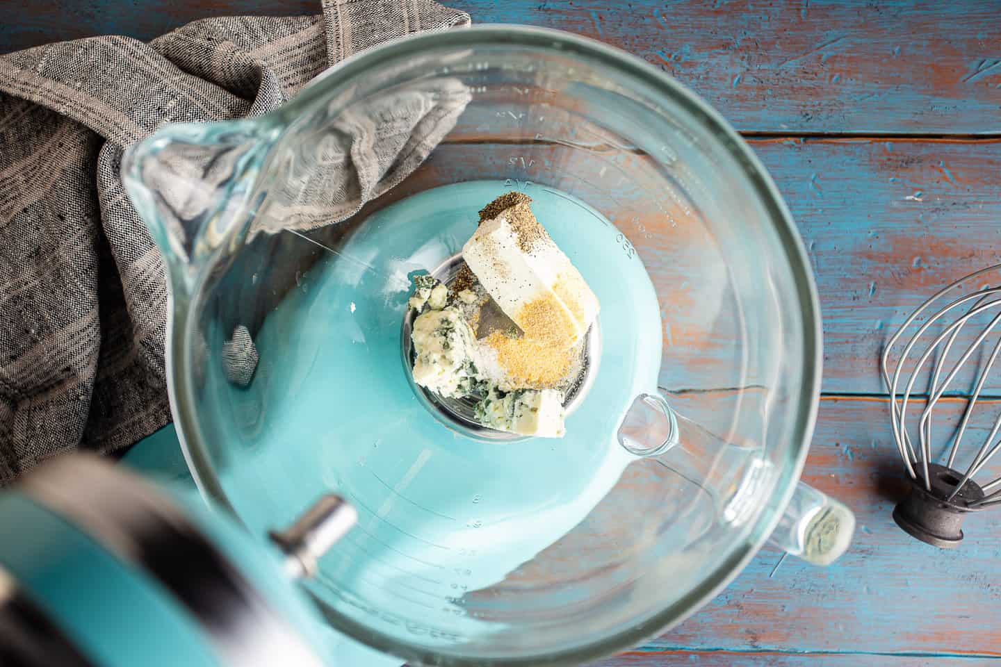 Cream cheese, blue cheese, and seasonings in a large glass mixing bowl.