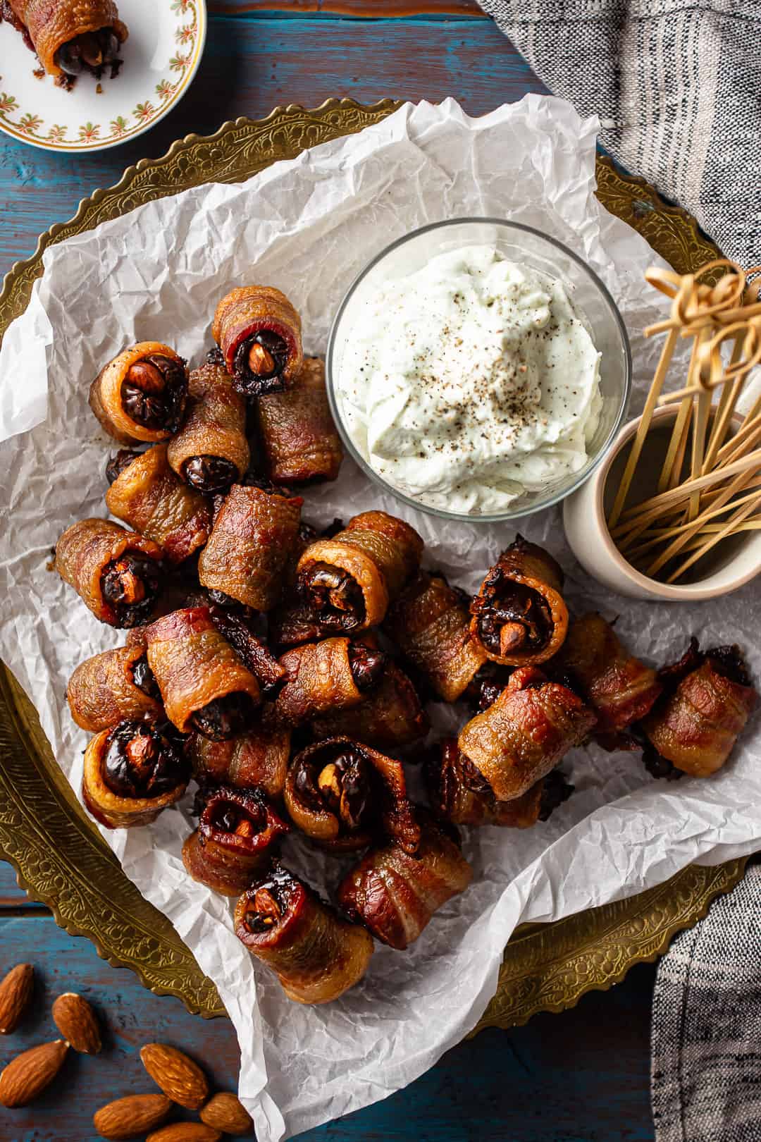 Dates wrapped in bacon and served on a vintage brass platter, with picks and a bowl of whipped blue cheese for dipping.