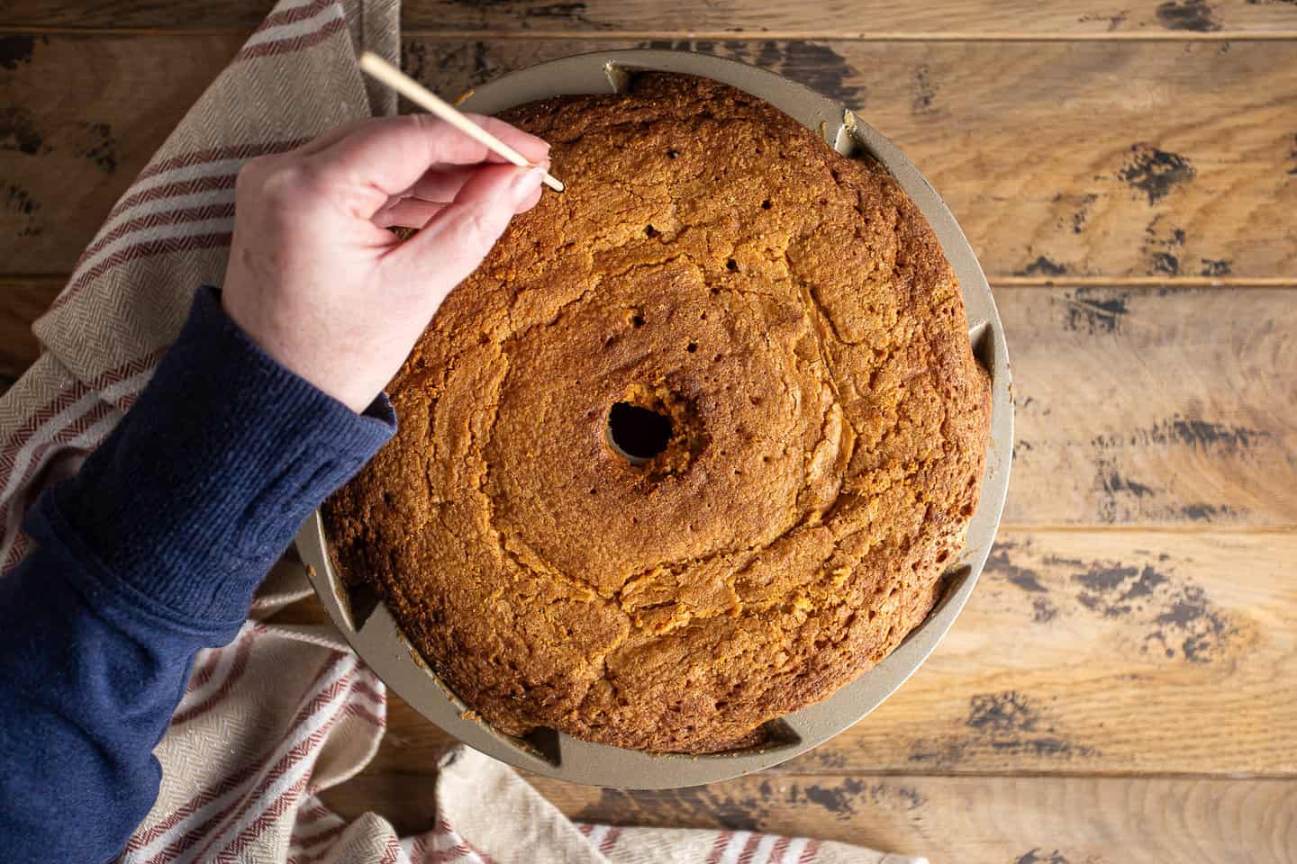 Poking holes in the bottom of a rum cake with a bamboo skewer.