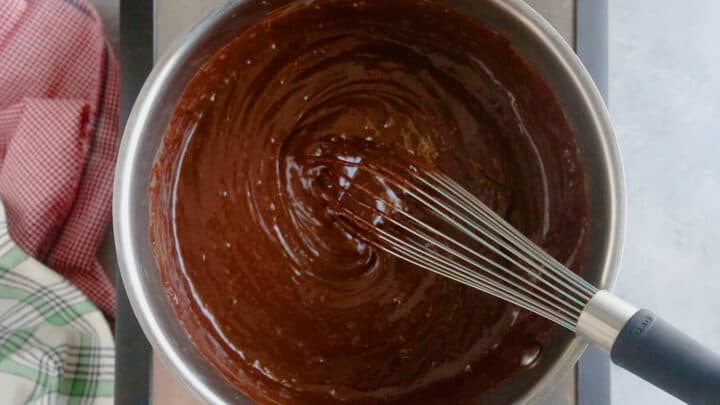 Thickened fudge in a pot with a whisk.