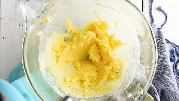 Butter, sugar, and eggs, blended together in a large glass mixing bowl.