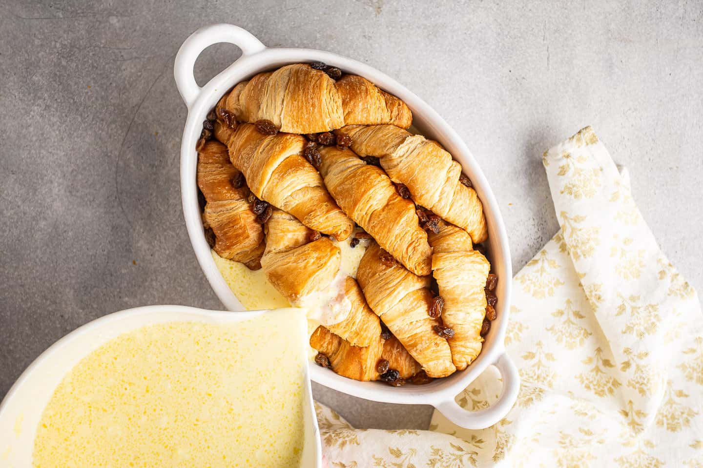 Pouring custard over croissants.