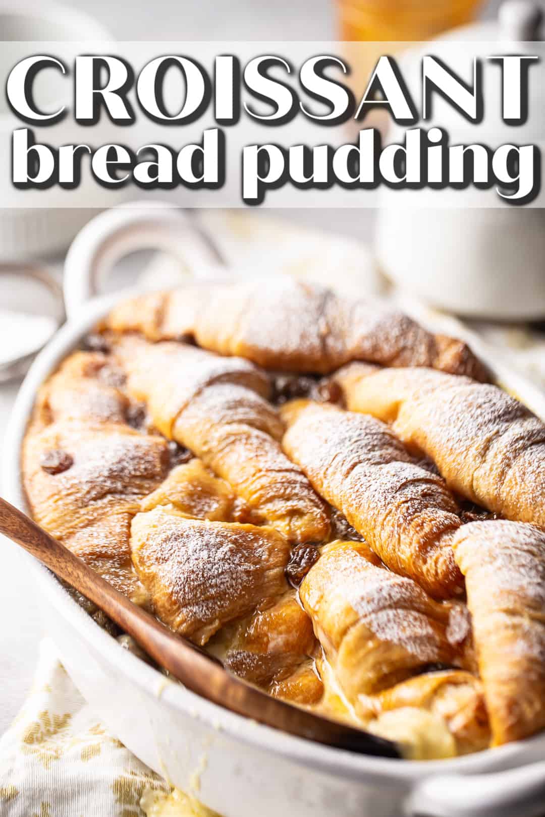 Croissant bread pudding recipe, prepared and presented on a white background with a dusting of powdered sugar.