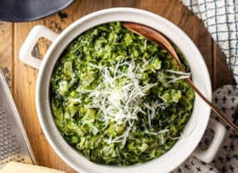 Creamed spinach in a ceramic pot with parmesan cheese.
