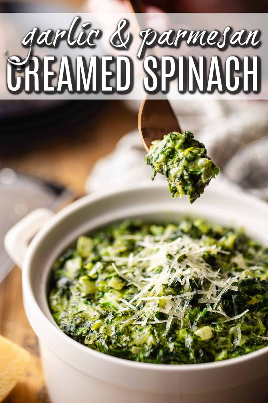 A forkful of creamed spinach being lifted from the serving dish.