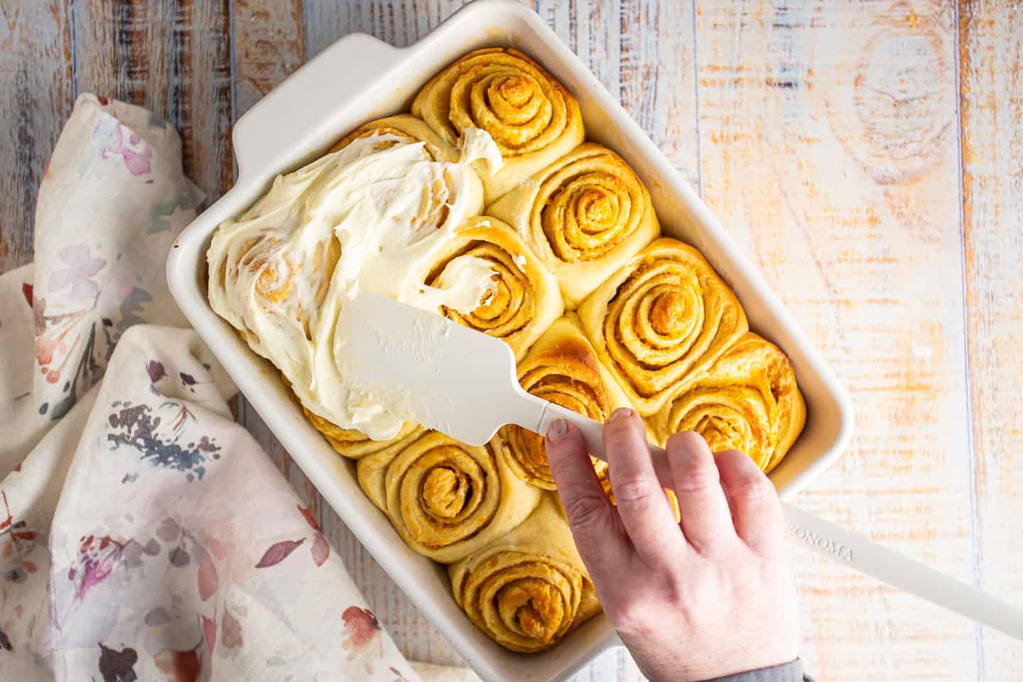 Topping orange rolls with cream cheese icing.