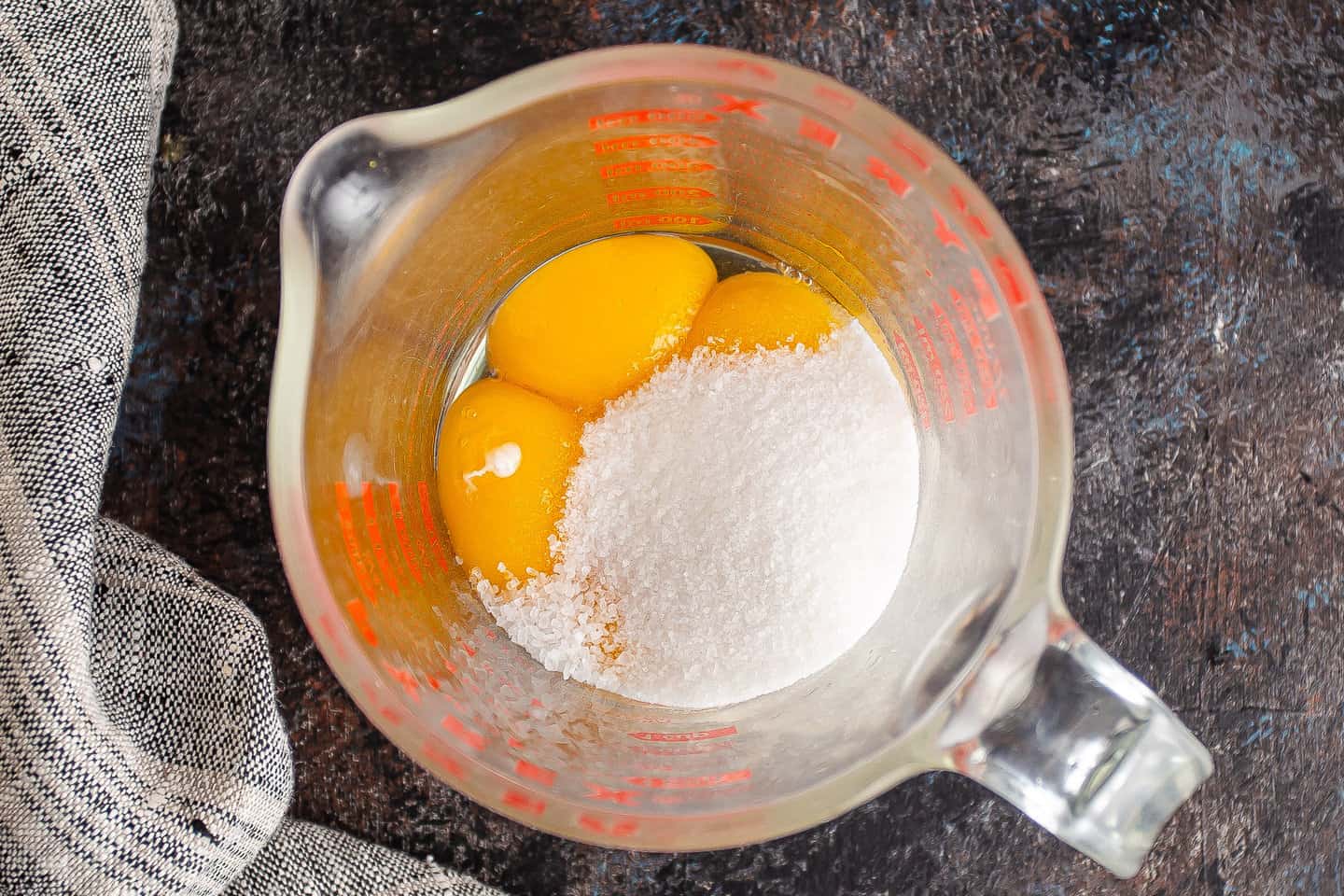Egg yolks, sugar, and salt in a large glass measuring cup.