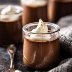 Chocolate pot de creme served in a glass jar with whipped cream on top.
