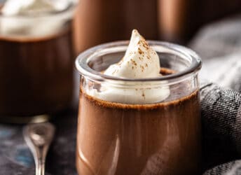 Chocolate pot de creme served in a glass jar with whipped cream on top.