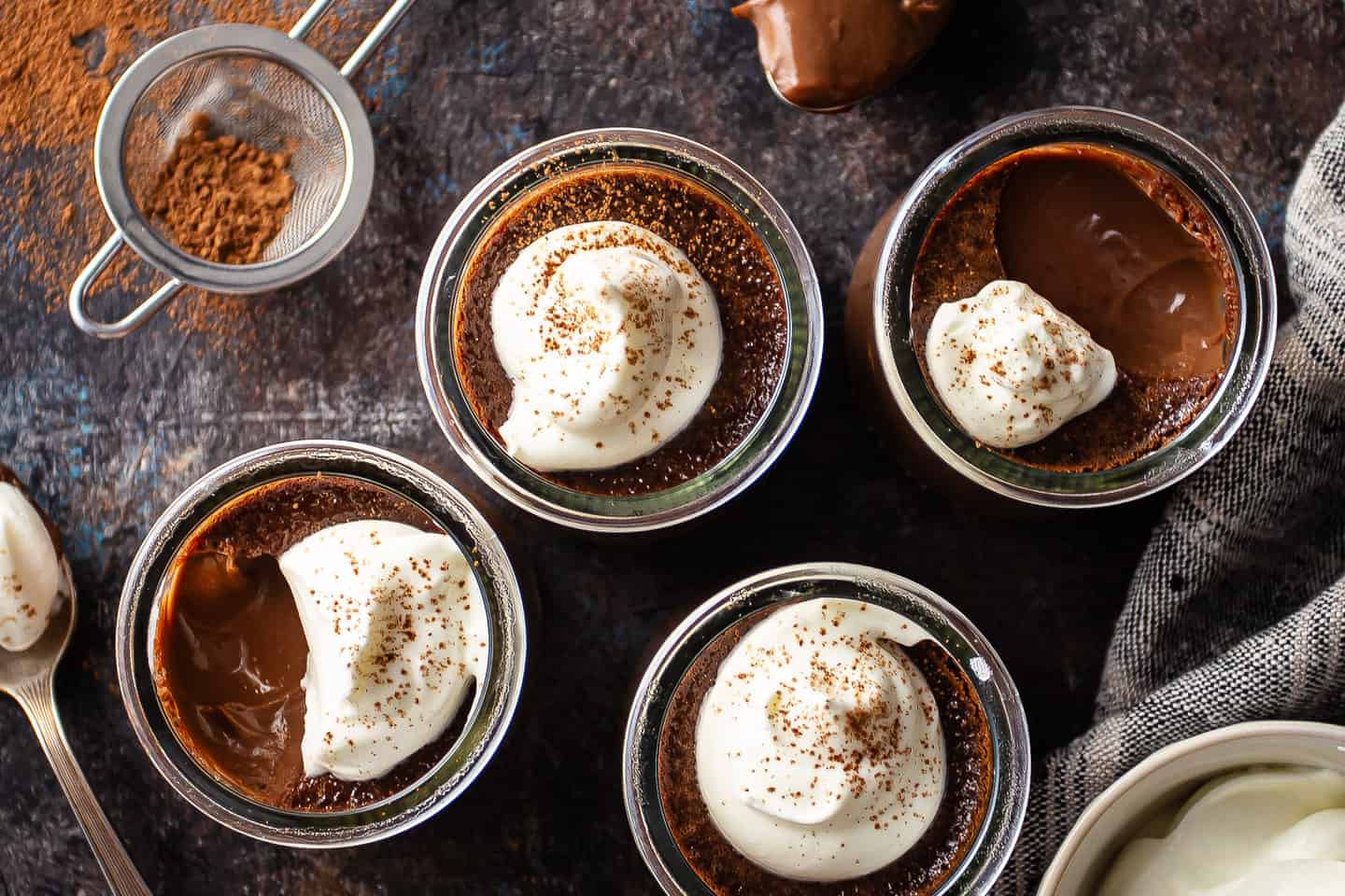 Pot de creme recipe, prepared in individual glass jars and dusted with cocoa powder.