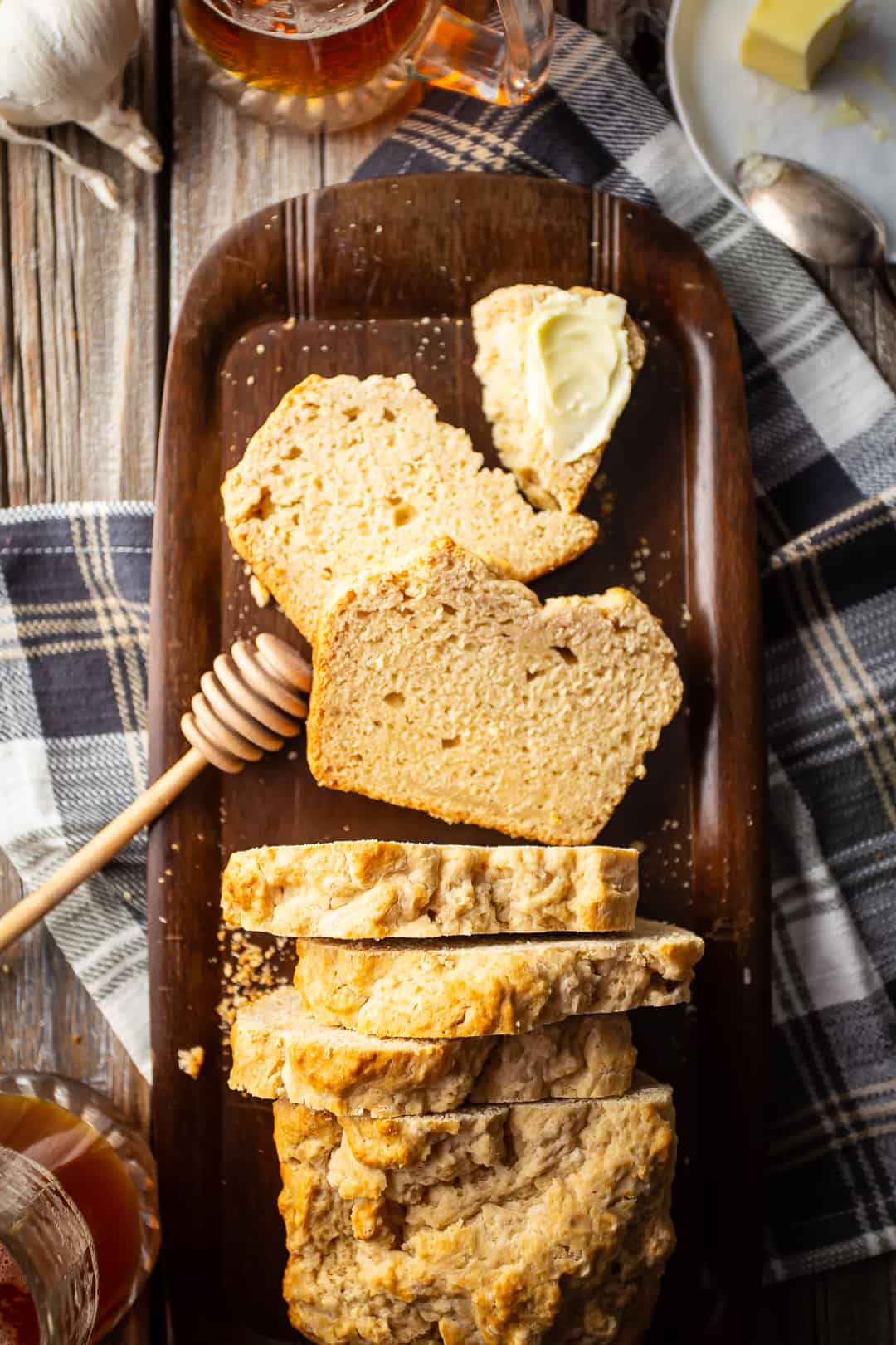 Recipe for beer bread, prepared, sliced, buttered, and served on a wood tray.