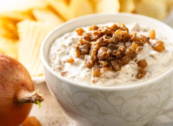 French onion dip presented in a bowl with potato chips in the background.