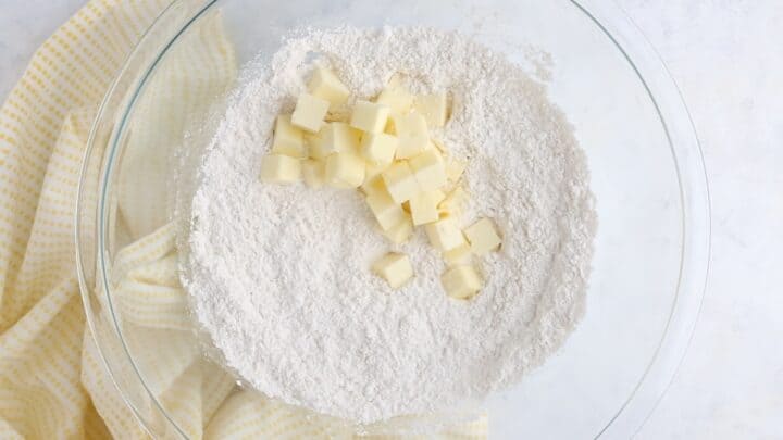 Adding cold, cubed butter to the dry ingredients.