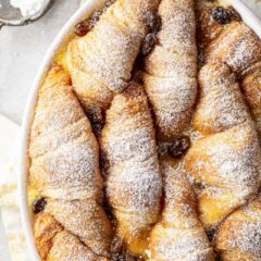 Bread pudding with croissants recipe, speckled with golden raisins and dusted with powdered sugar.