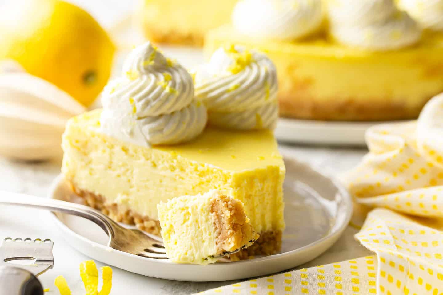 Best lemon cheesecake recipe, sliced and served with a bite taken out.