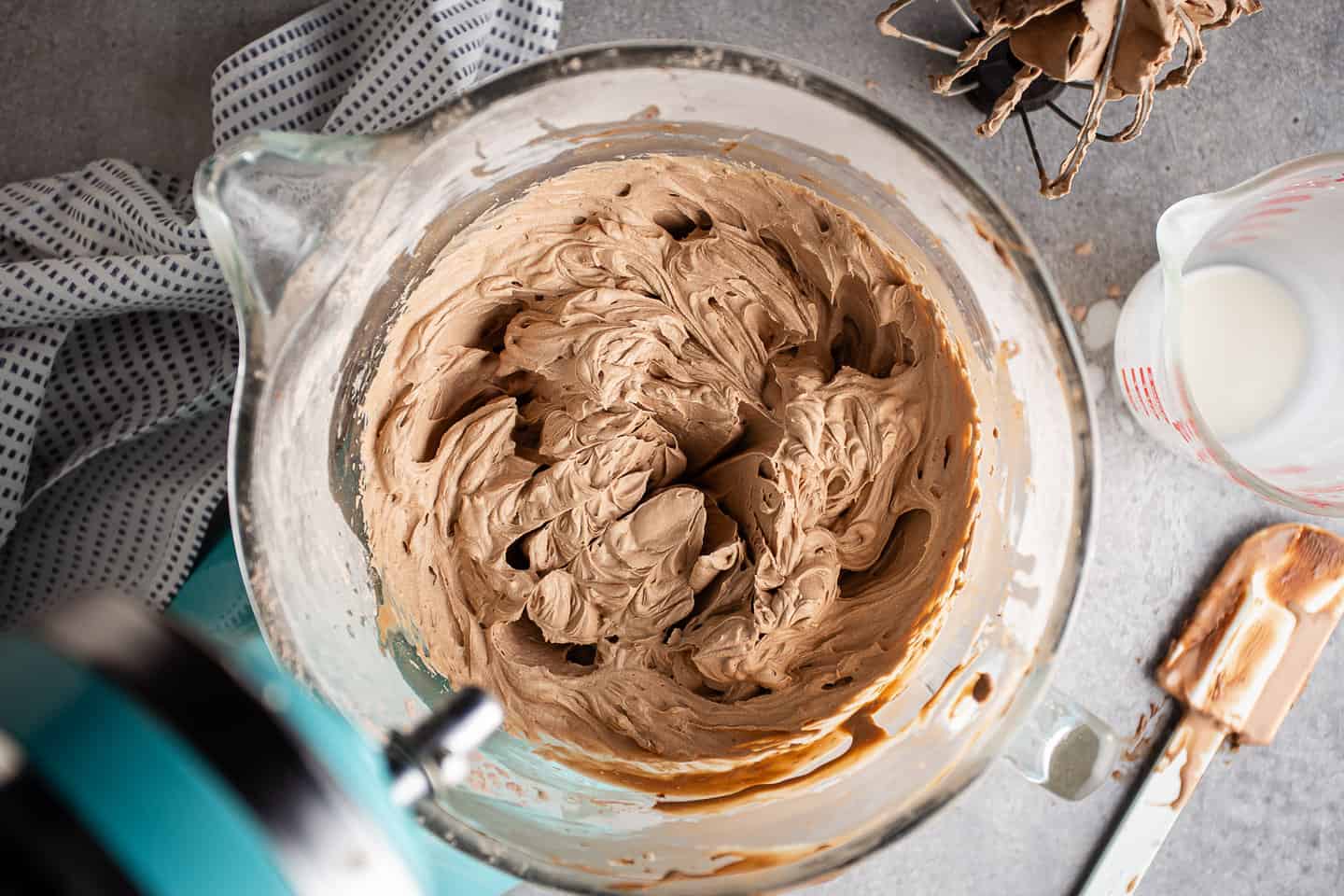 Freshly made chocolate whipped cream frosting in the bowl of a stand mixer.