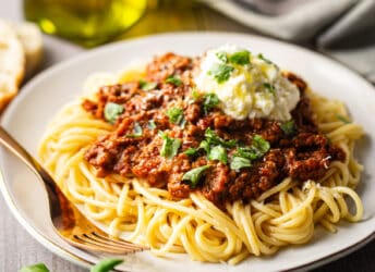 Bolognese sauce served over cooked spaghetti with a dollop of ricotta.