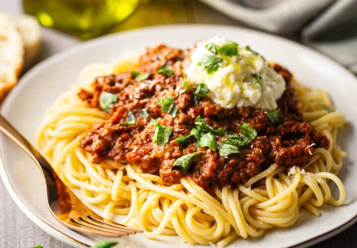 Bolognese sauce served over cooked spaghetti with a dollop of ricotta.
