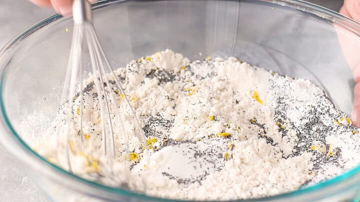 Stirring dry ingredients for lemon poppy seed muffins together with a whisk.