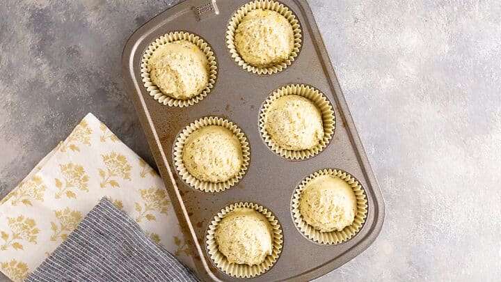 Unbaked lemon poppy seed muffins in  a standard-sized muffin tin.