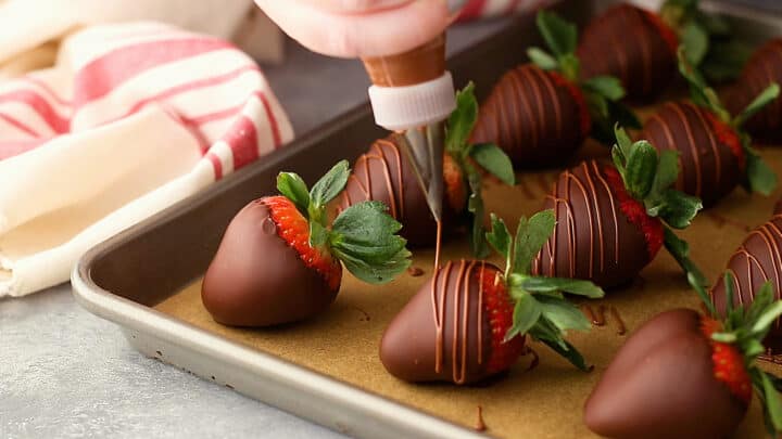 Drizzling milk chocolate over chocolate-covered strawberries, for garnish.