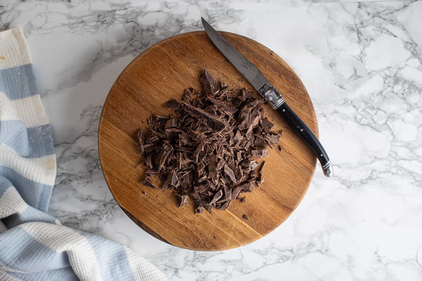 Chopped chocolate on a wooden cutting board.