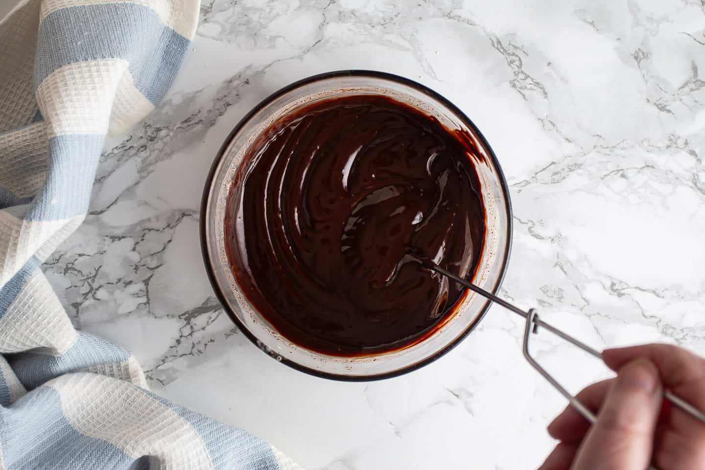 Freshly made ganache being whisked together in a glass bowl.