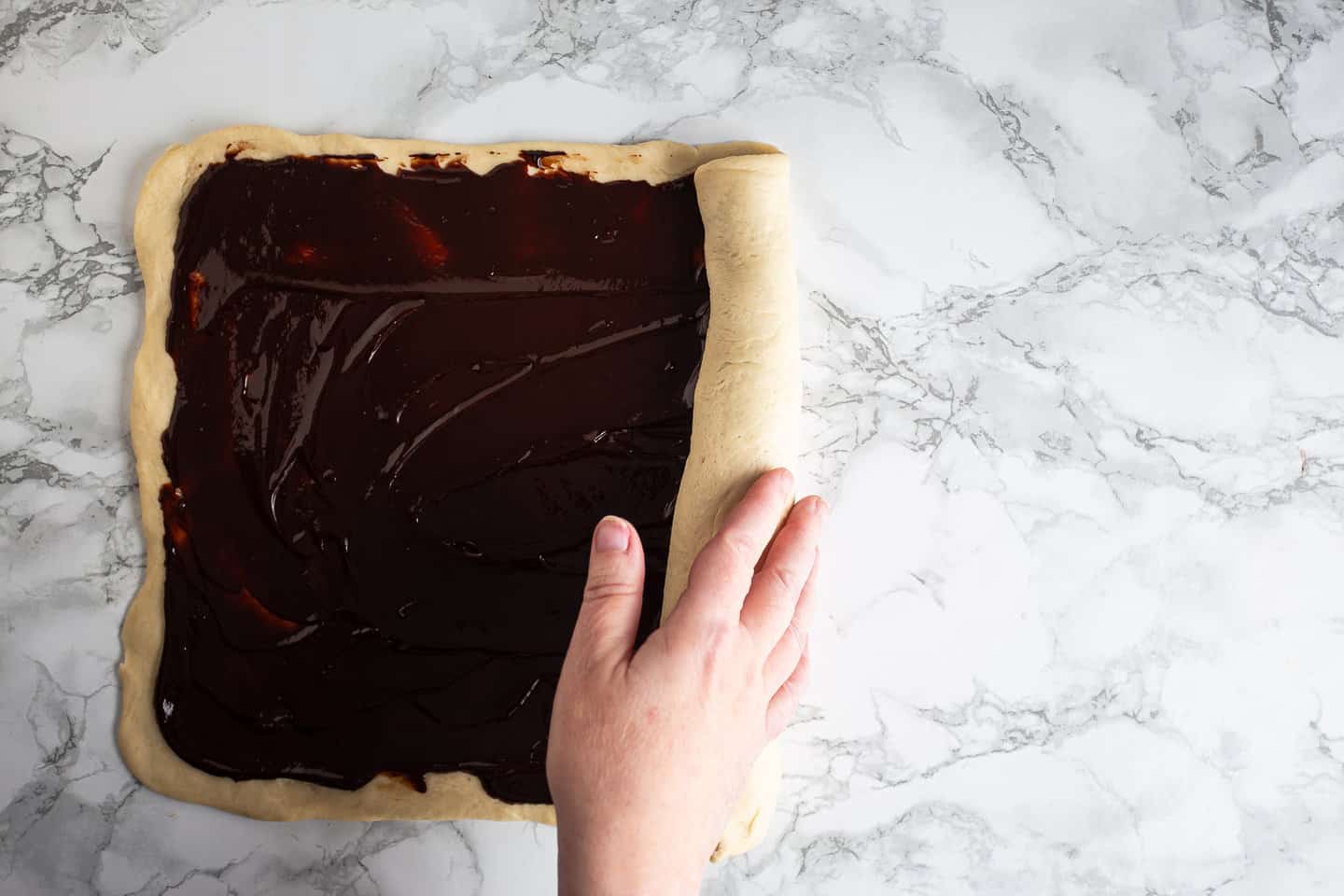 Rolling chocolate babka into a tight log.
