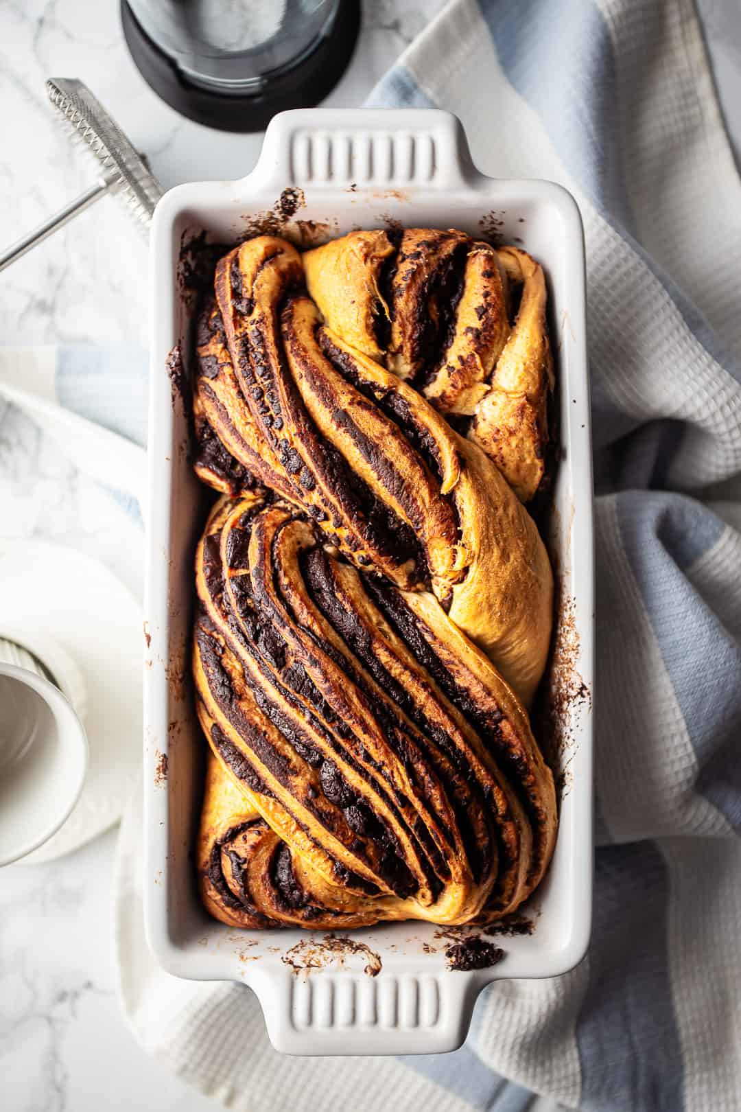 Babka chocolate bread presented on a white marble surface.