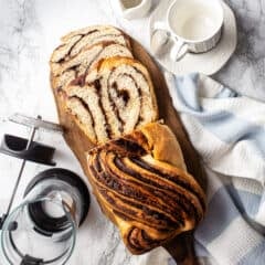 Homemade chocolate babka on a wooden board with a French press coffee pot.