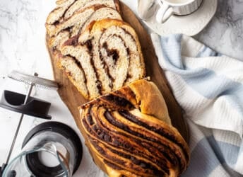 Homemade chocolate babka on a wooden board with a French press coffee pot.