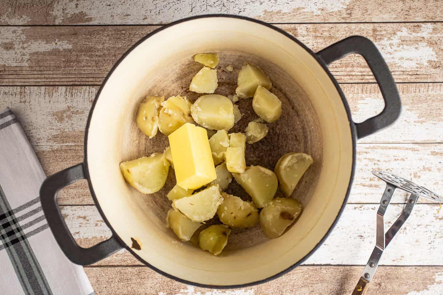 Boiled, drained potatoes in a pot with butter.