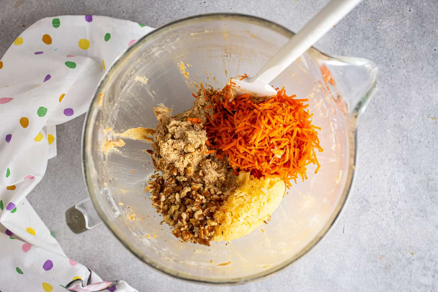 Adding carrots, pineapple, and walnuts to carrot cake batter.