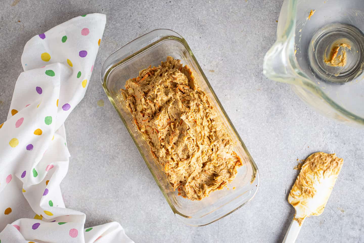 Carrot cake batter in a glass loaf pan.