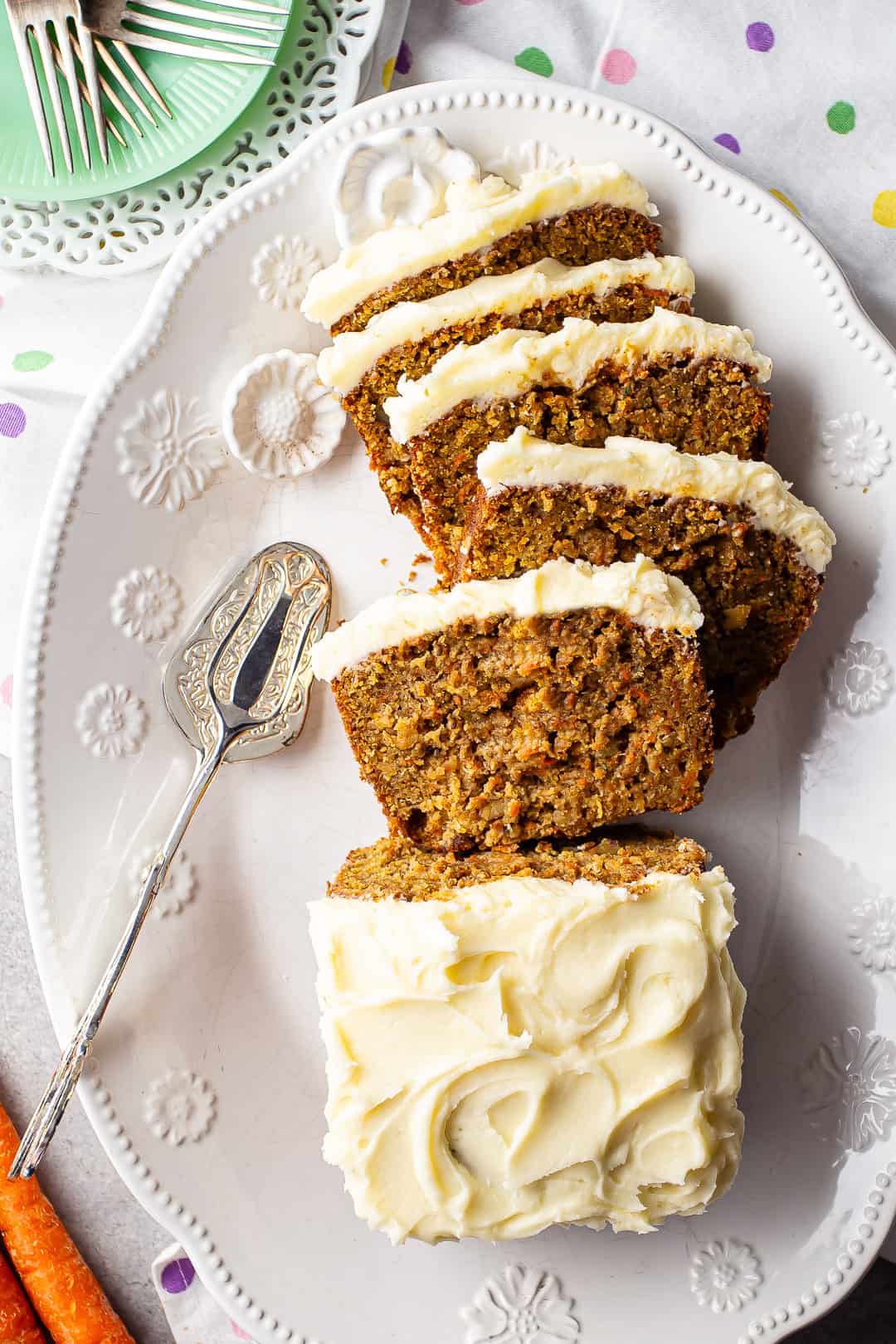 Carrot loaf cake with cream cheese frosting on a white oval platter.