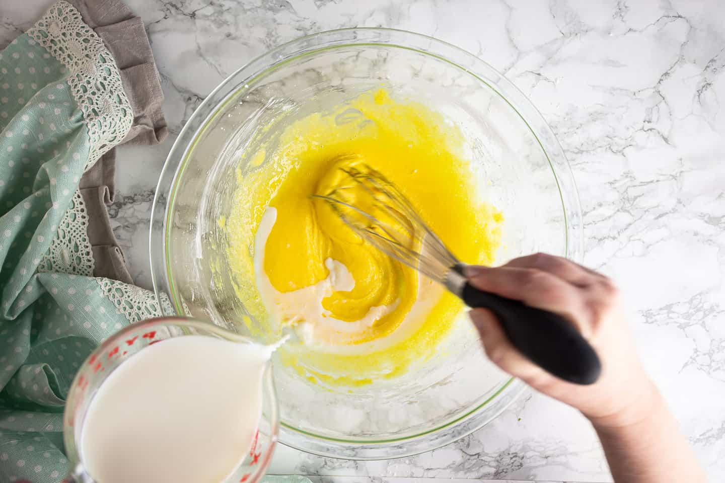 Tempering egg yolks with hot milk.