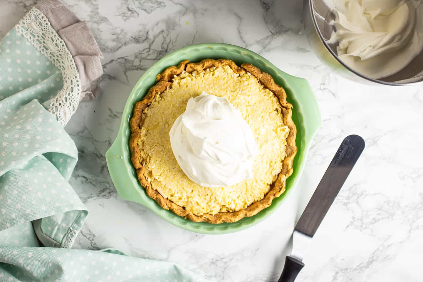 Topping coconut cream pie with freshly whipped cream.