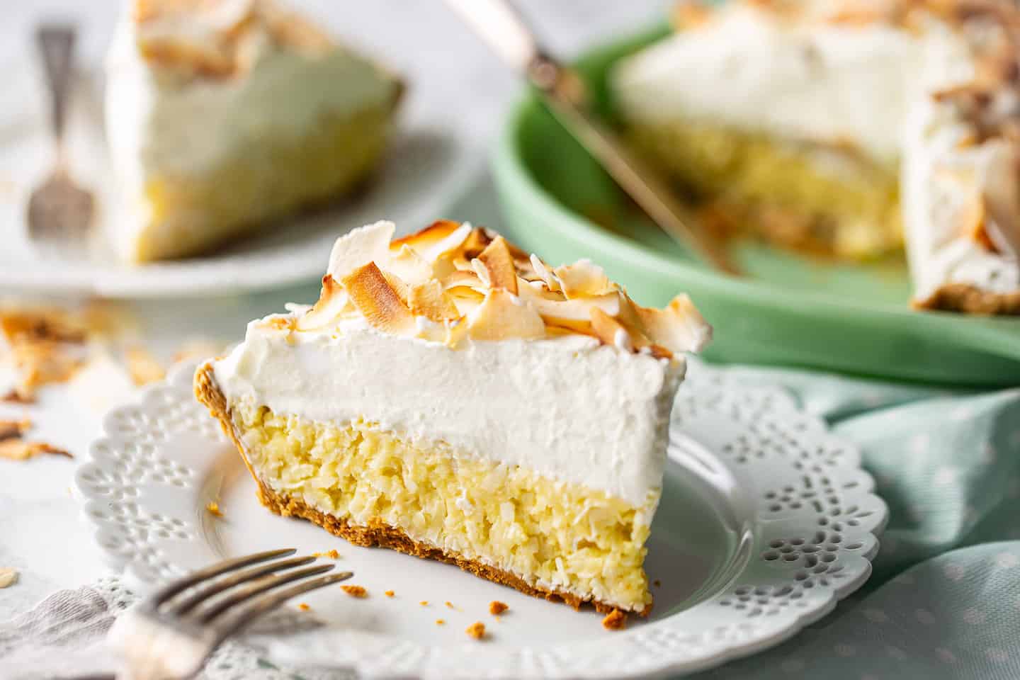 Easy coconut cream pie, assembled, sliced, and served on a marble background.