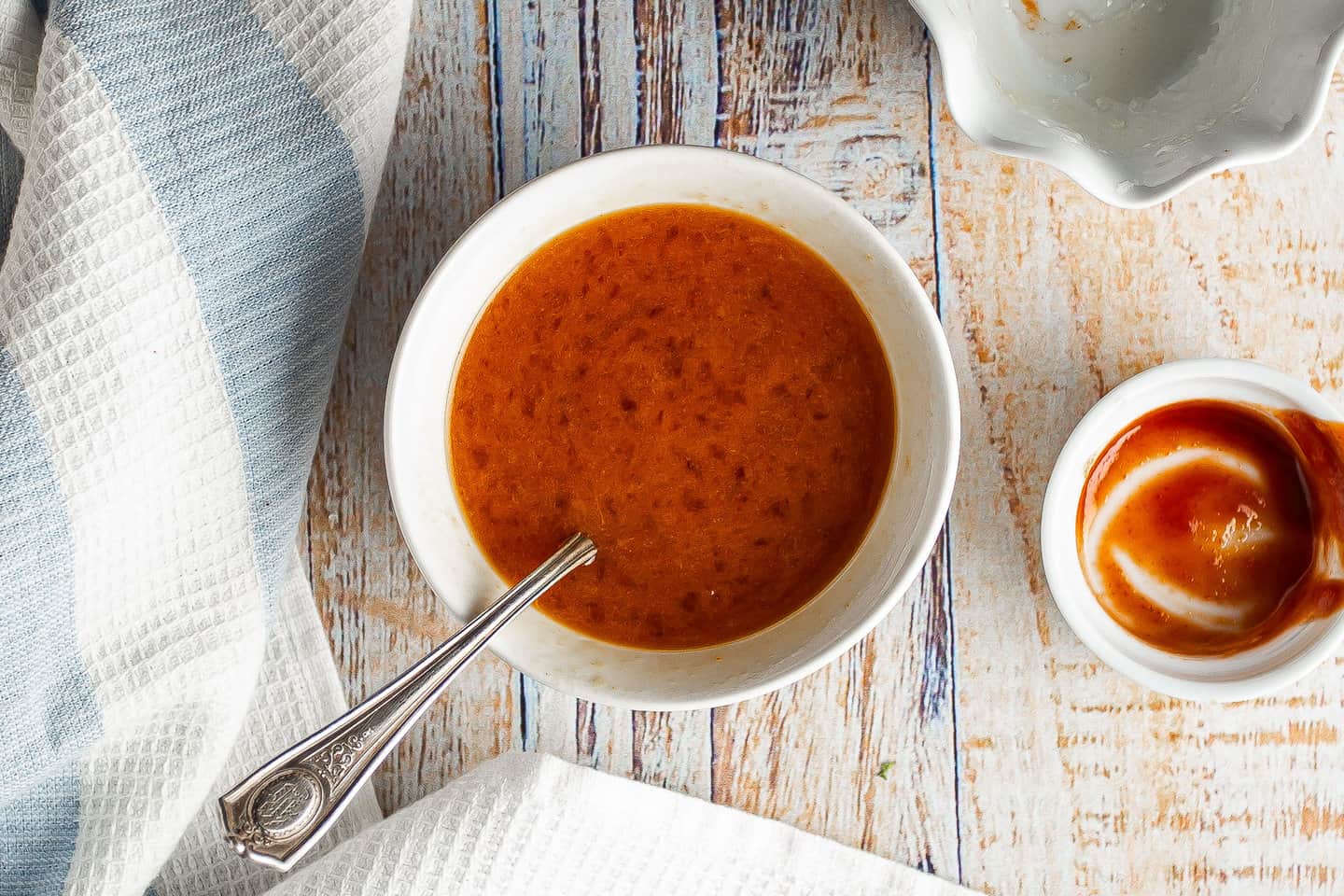 Orange Sriracha glaze in a small white bowl.