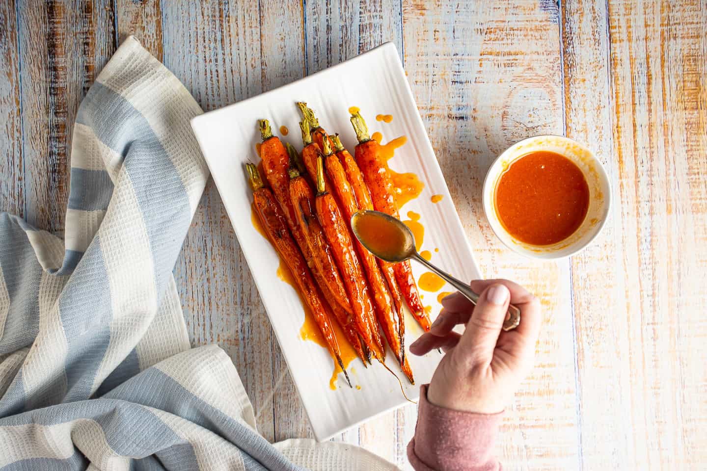 Drizzling a sweet and spicy glaze over roasted carrots.