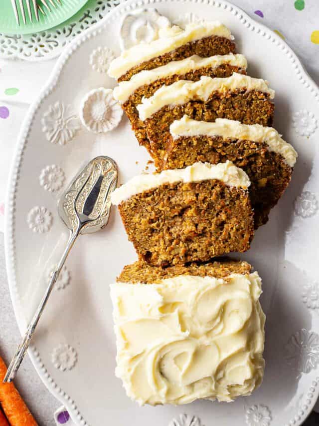 Carrot loaf cake with cream cheese frosting on a white oval platter.