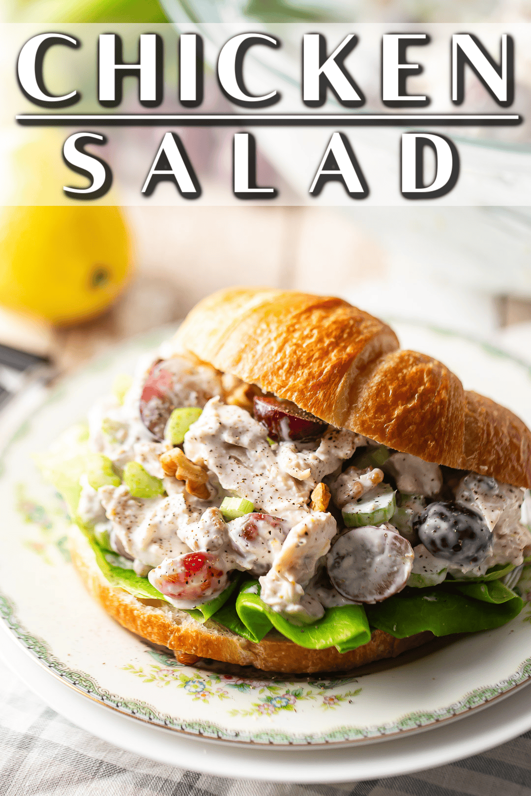 Chicken salad with celery, grapes, and nuts, served on a croissant with a pale background.